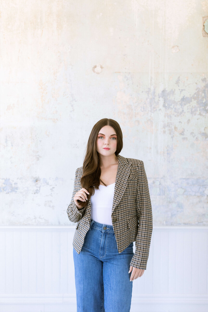 Girl with dark hair wearing tweed blazer and denim posing in photo studio
