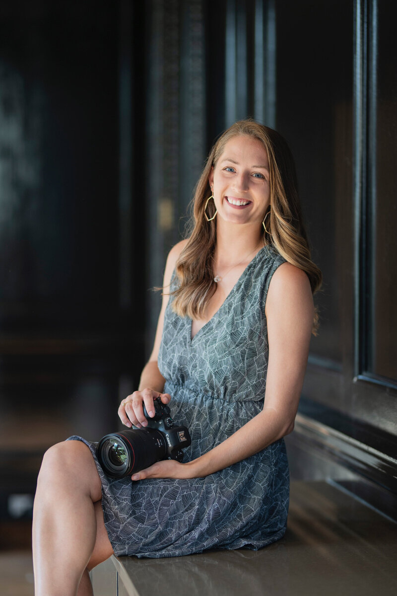 A person sitting on a bench smiling with a camera in their lap
