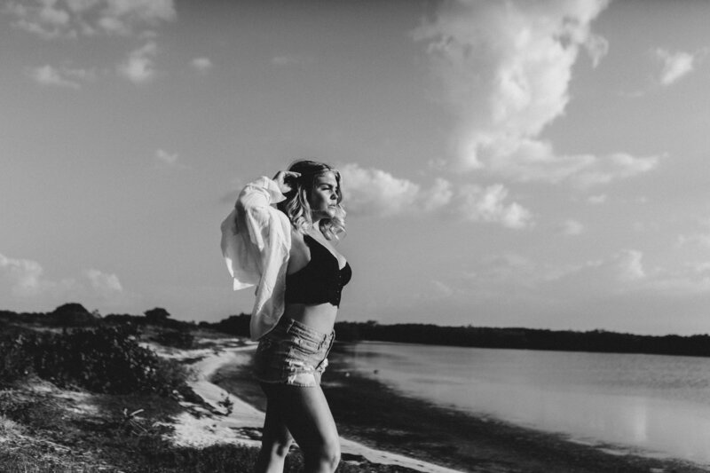 A woman stands on the beach chest lifted embracing who she is with confidence.