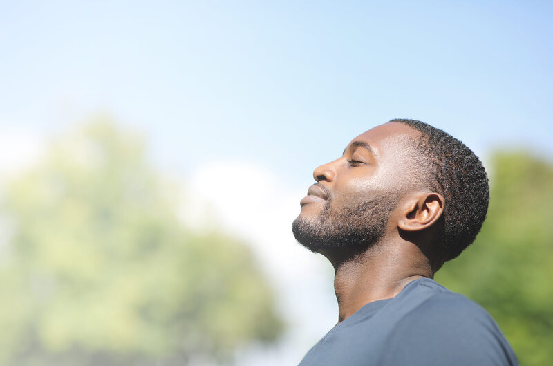 Smiling man with eyes closed and face tilted toward the sun