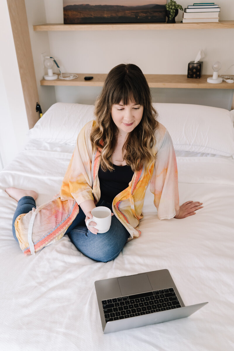 Woman on her laptop sitting on a bed