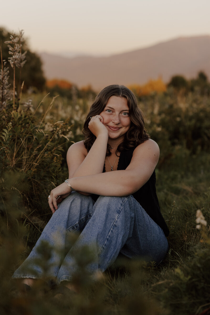 girl poses in field at sunset senior photos in white mountains of new hampshire