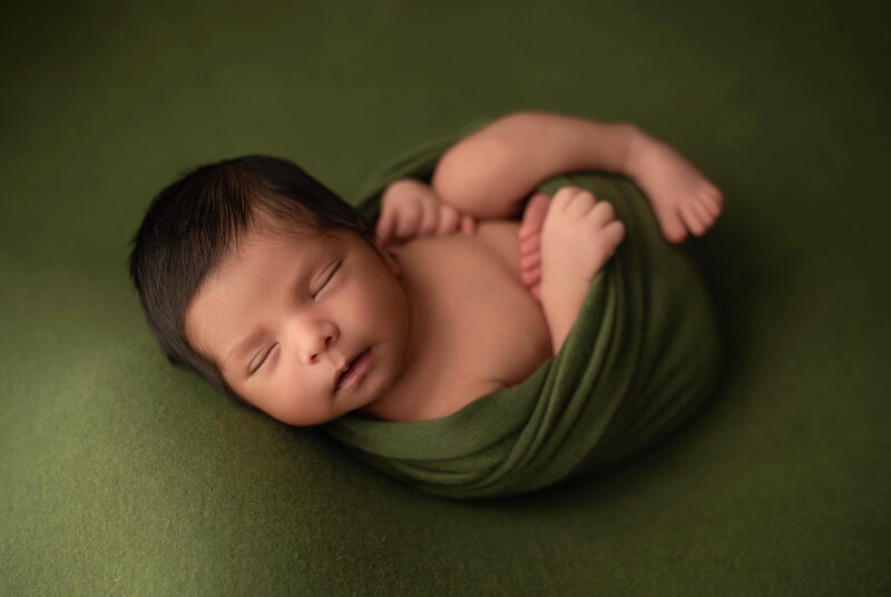 Los Angeles Newborn Photography - newborn baby wrapped in green fabric on a green backdrop