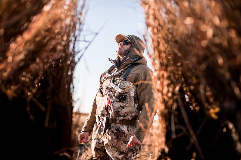 Hunter wearing camouflage gear standing in a waterfowl blind during a Kansas duck hunt