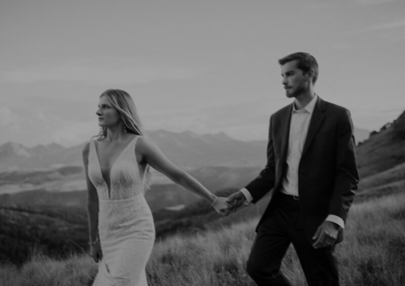 Bride and groom walk through the San Juan Mountains holding hands