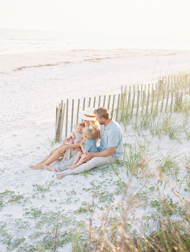 Family of four sitting together on the beach with ocean in the background
