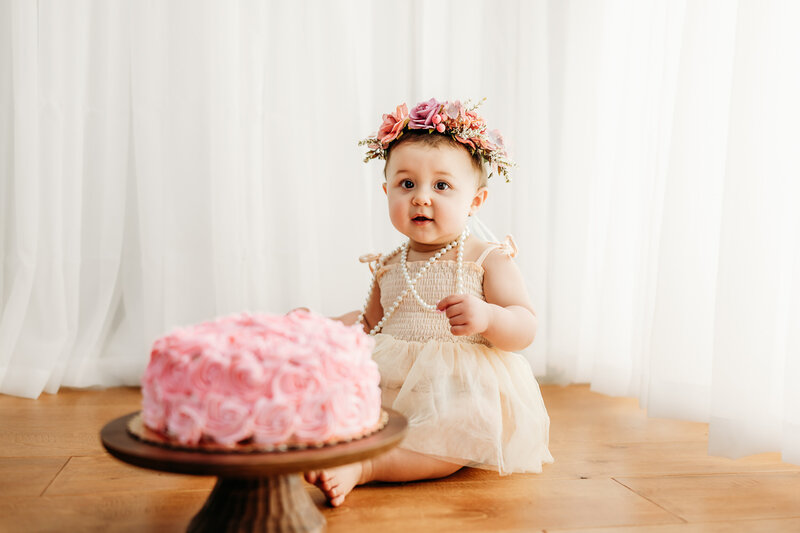 1st birthday cake smash for this little girls studio photography session! she has a floral crown and a pink cake