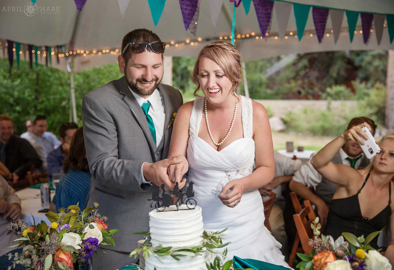 Bride and groom cut their cake in the white tent on their wedding day at Estes Park Condos on Fall River