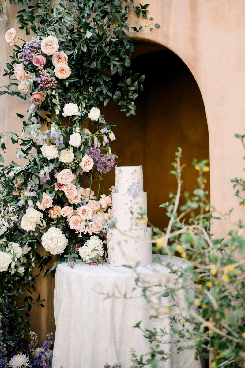 Elegant wedding cake surrounded by lush floral arrangement - fine art Scottsdale wedding photographer.