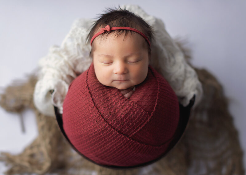Newborn baby girl sleeping in bucket rustic red