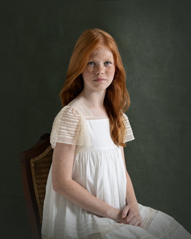 canvas fine art portrait of middle school girl with dramatic lighting against green backdrop.