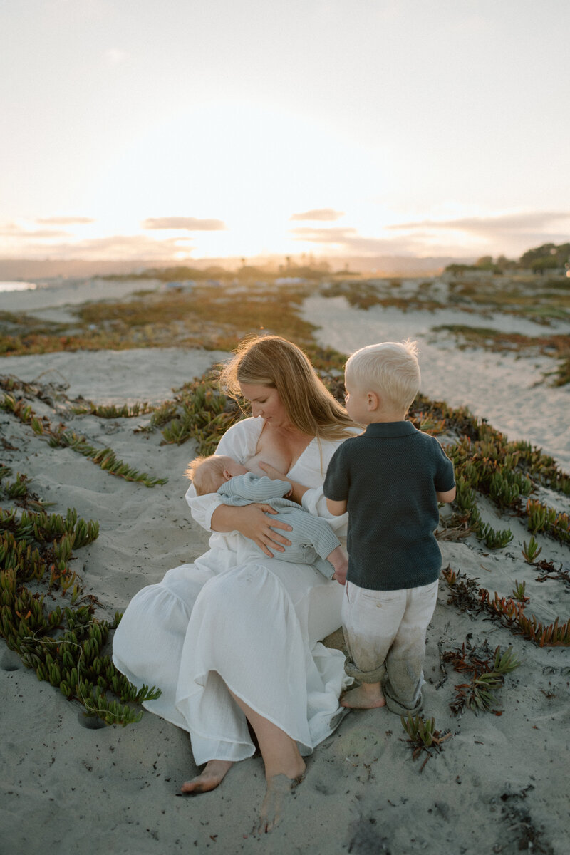 Molly, a San Diego Photographer  holding her baby close, gently resting her hand on the baby’s head