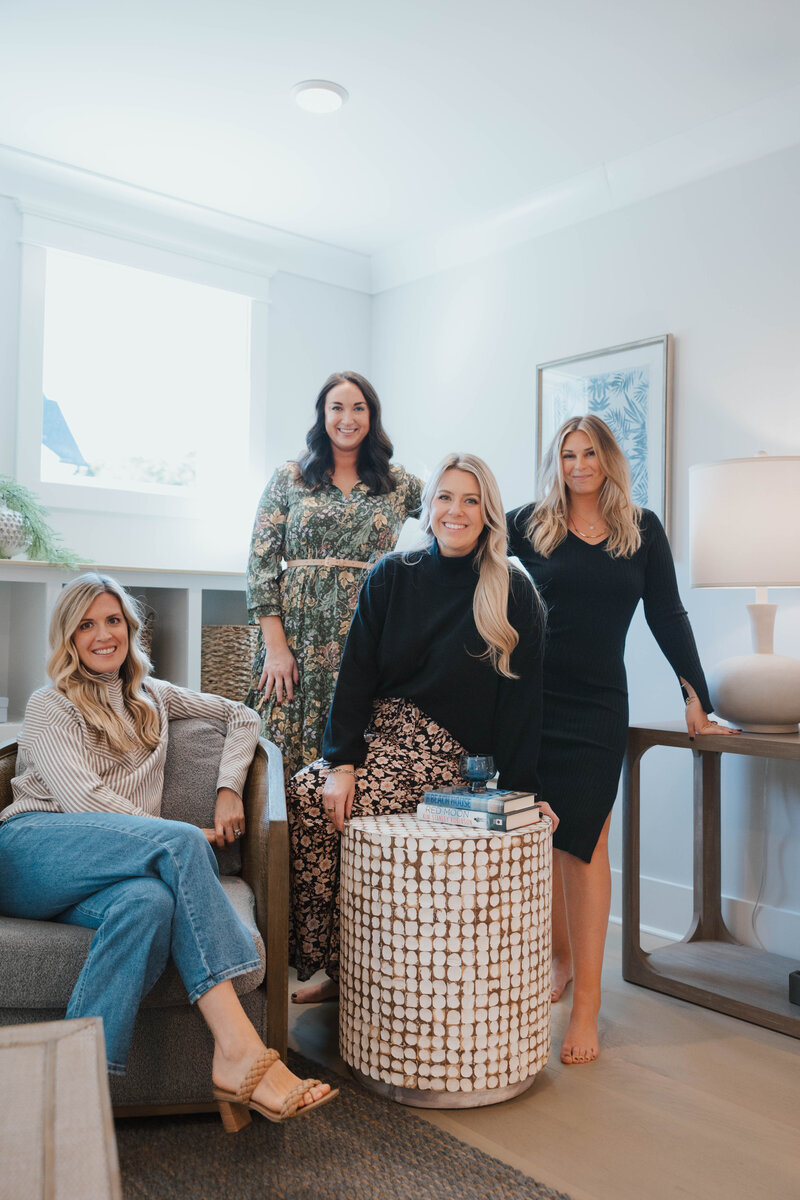 Raleigh Real Estate Agent, Jacie Dykes, wearing black dress sitting in modern living room in Raleigh New Construction home.