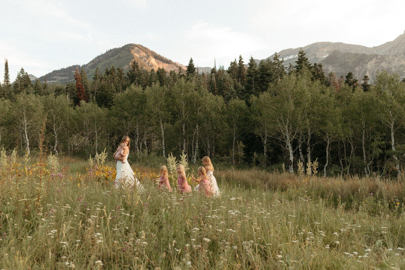 Mother holds her baby with her four daughters walking behind them at