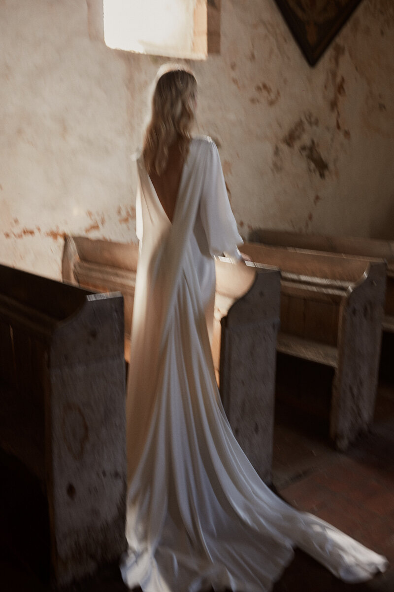Long sleeve silk wedding dress with deep v back on bride in church