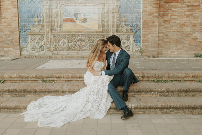 Bride and Groom sitting on the steps of a antique travel location during their wedding in Seville Spain