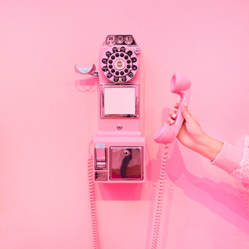 Vintage pink telephone mounted on pink wall
