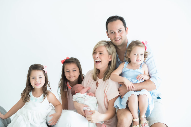 family of 6 laughing at white studio during newborn portraits