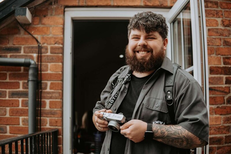Photographer Tom Bowen smiling with camera
