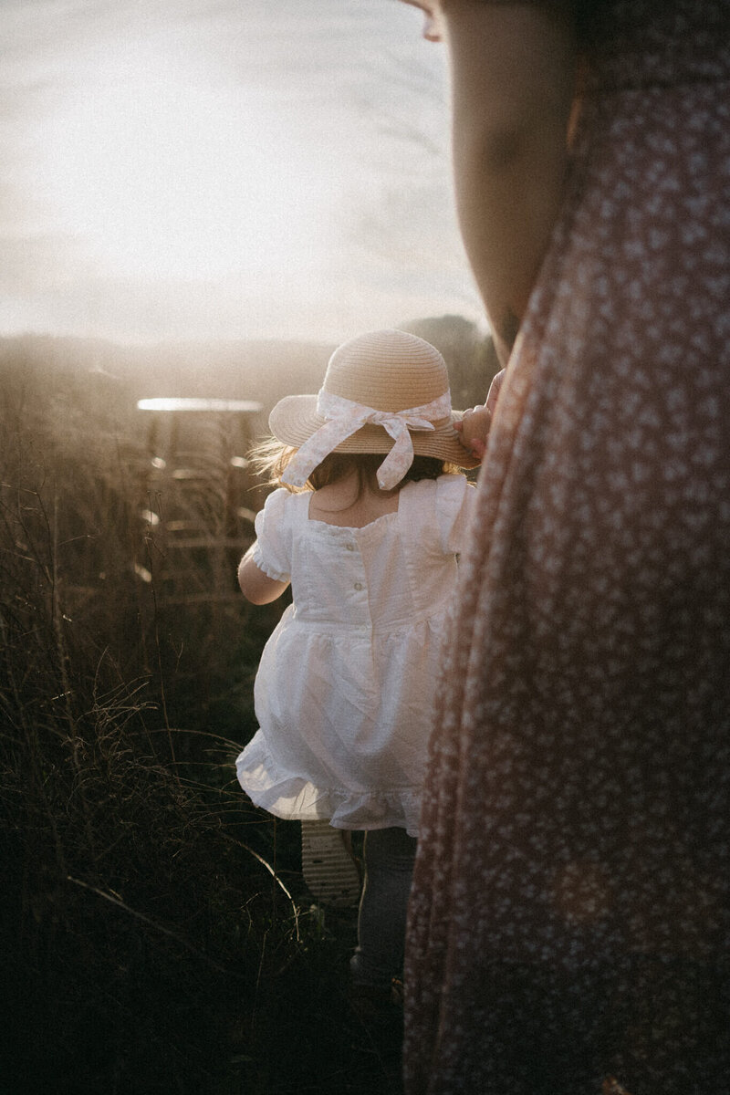 little girl in a sunhat walking in the sunset
