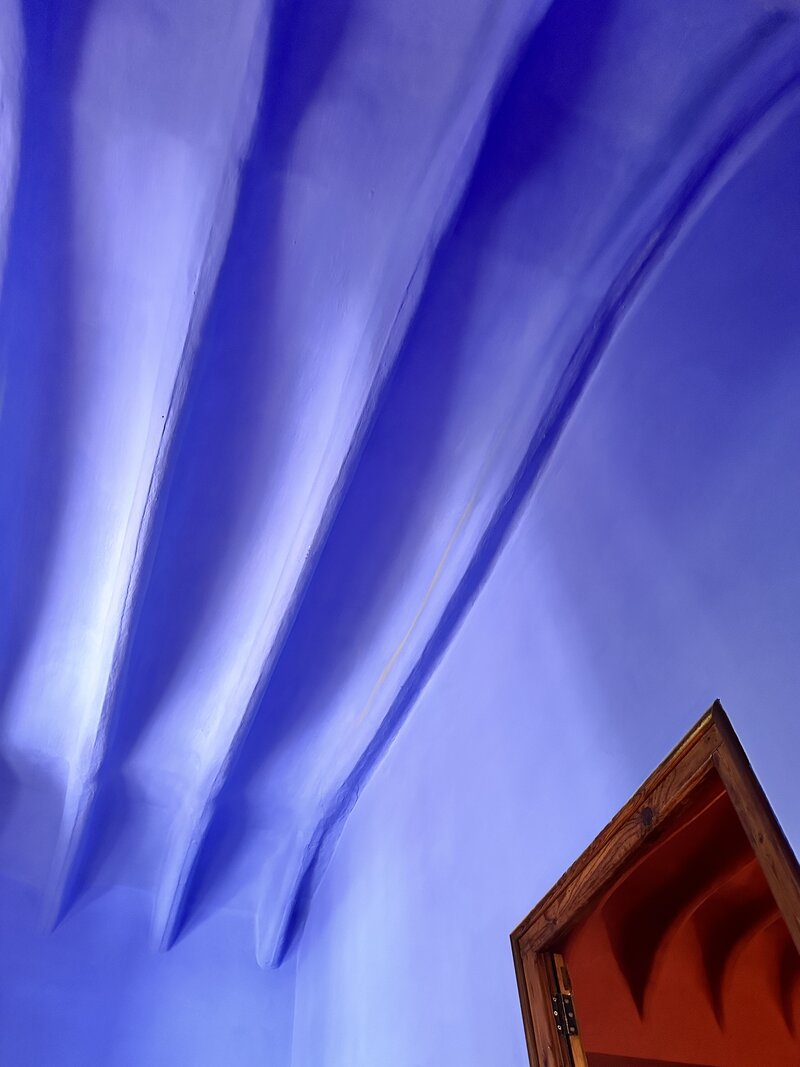 Photo of a room designed by Gaudí in Park Guëll in Barcelona: Saturated blue, with ripples in the ceiling, and a red door.