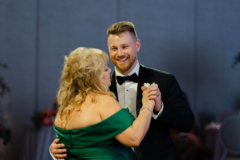 Ottawa wedding photos of the mother of the groom in a green dress dancing with her son during his Chateau Le Parc wedding reception