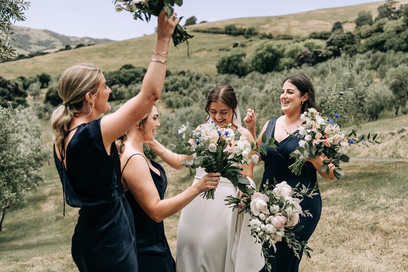 bride and bridesmaids in navy dance in olive trees at mt vernon lodge in akaroa