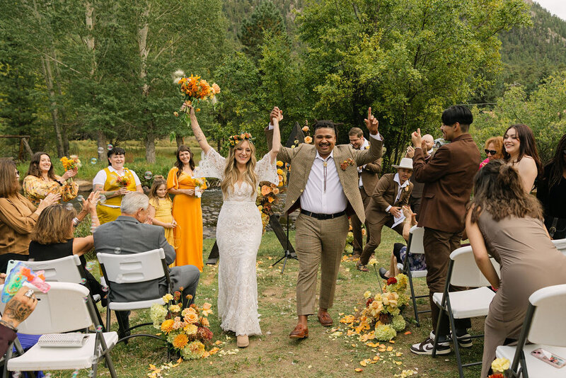 Joyful wedding ceremony recessional with yellow floral details and natural celebration at Venue on The Rocks