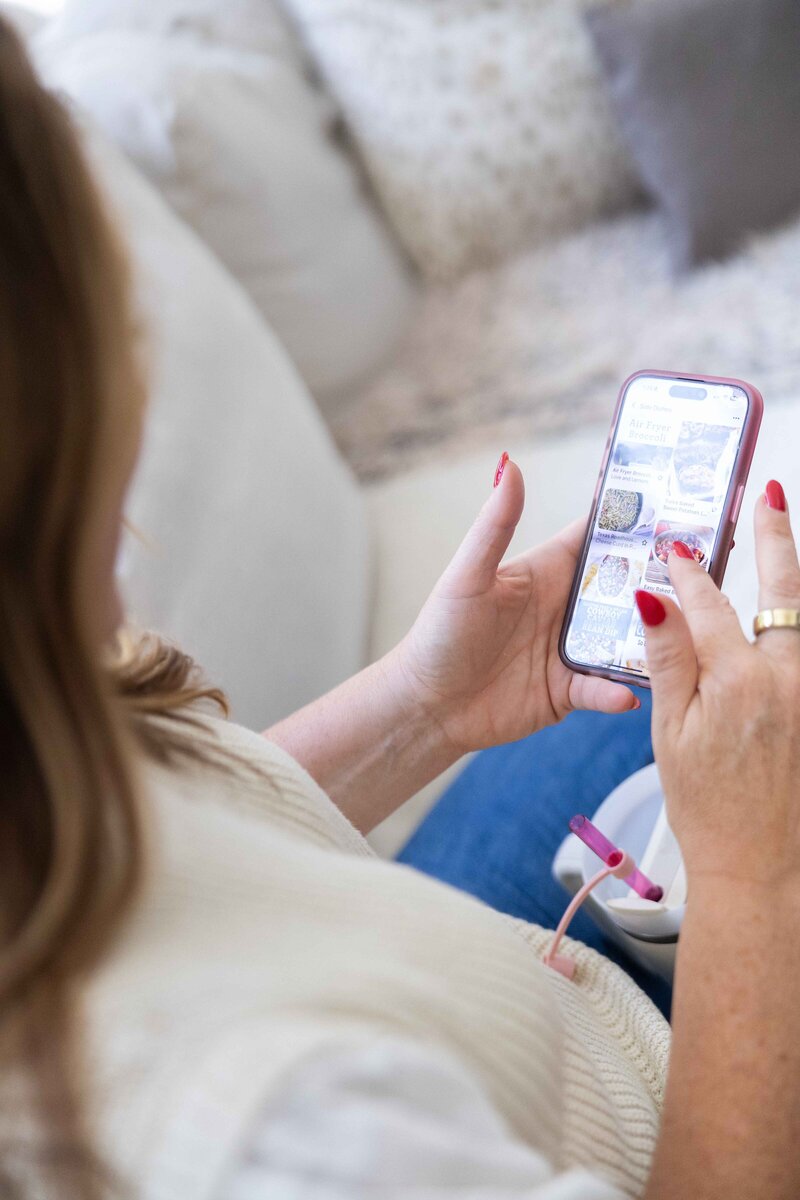 woman with dark hair on white couch on her phone