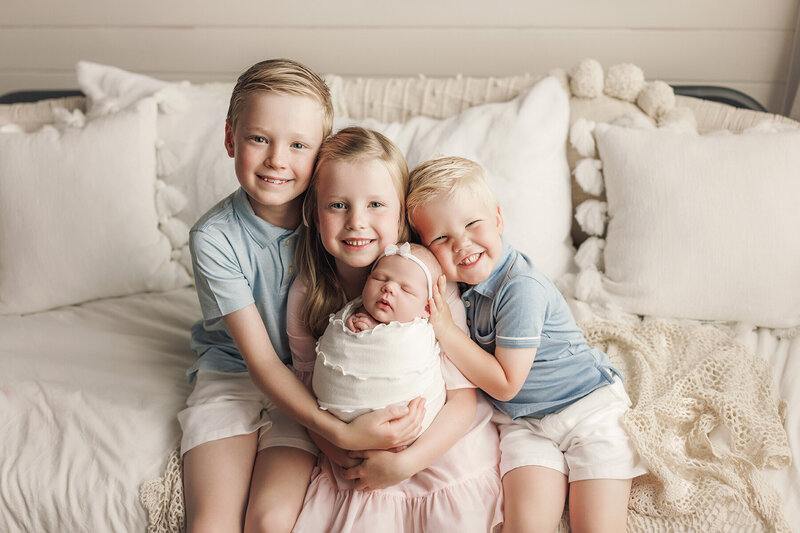 Siblings hold their brand new baby in Fort Collins area photography studio.