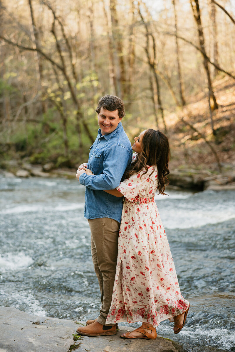 Couple hugging by the water during Tennessee mountain engagement session