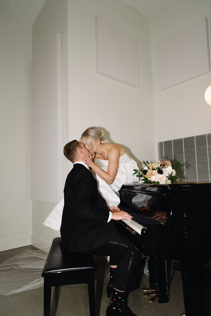 Romantic wedding photo of a couple kissing on a grand piano—luxury storytelling with timeless elegance and soulful intimacy.