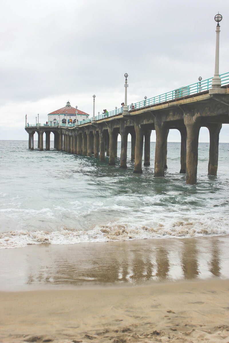 Manhattan Beach Pier extending over ocean waves on cloudy California day