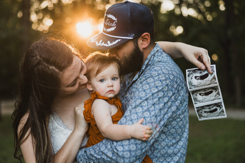 Pregnancy announcement of a mother, father and toddler at sunset with ultrasound. 