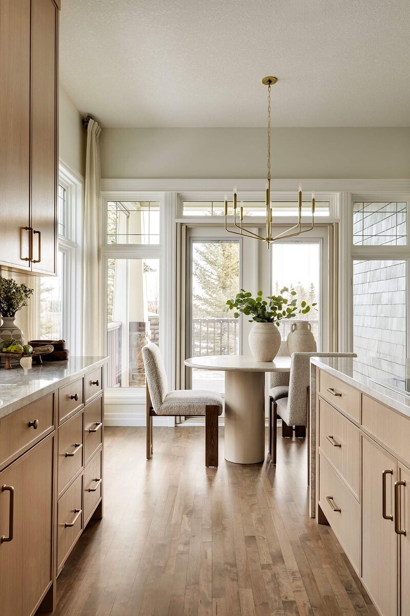 Stone dining table with gold chandelier and wood and upholstered dining chairs. 