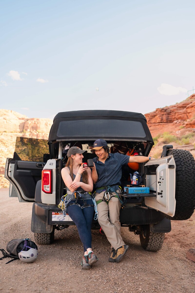 Couple taking a break from hiking in Moab during their adventure engagement session