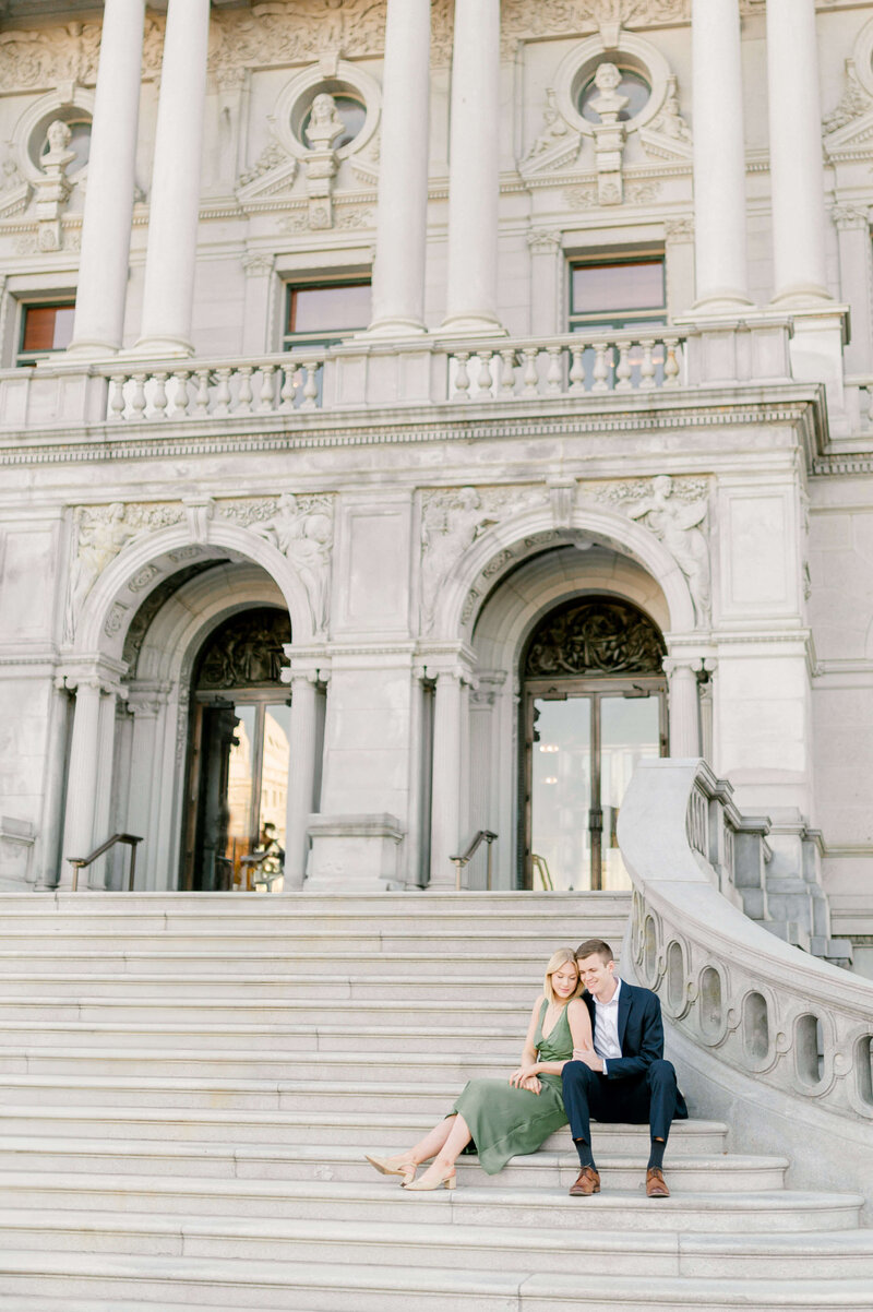 Engagement photo taken by Rachael Mattio of a couple sitting on the steps of the Library of Congress, located in DC