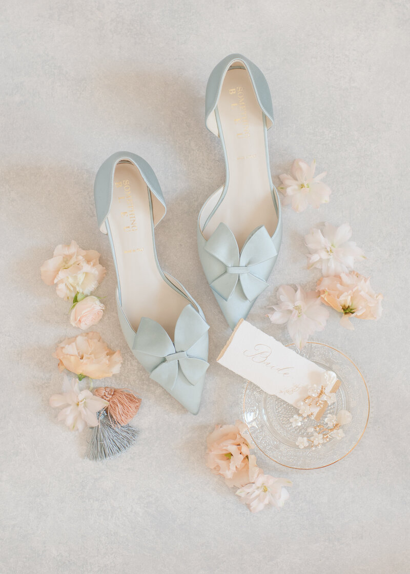 Travel Wedding Photographer,  Invitations and wedding accessories lay on a table, including slippers, earrings, and flowers