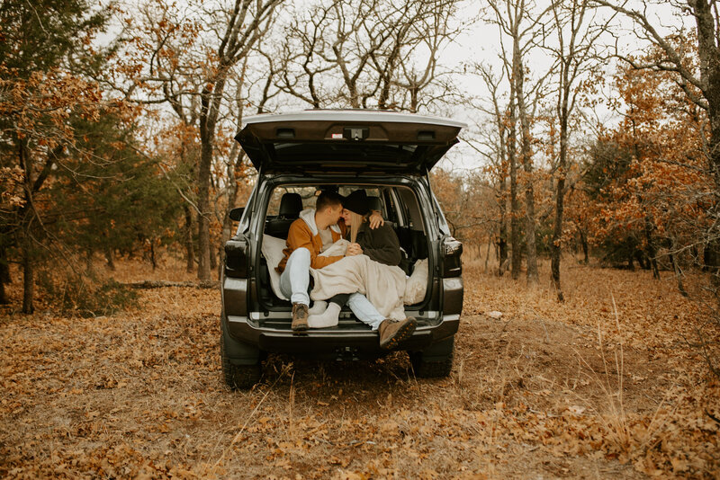 Couple sitting in trunk of their car cuddling up during a fall engagement session