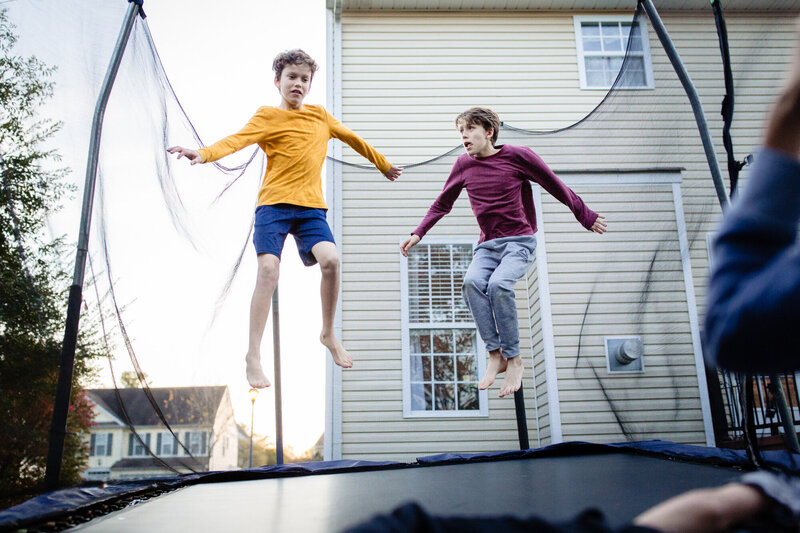 two tween brothers jump on their trampoline at home.