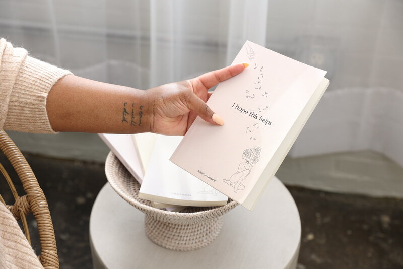 hand holding a white book titled, 'I Hope This Helps'