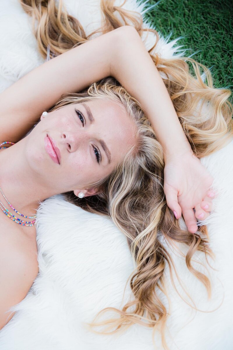 Fun senior portrait of a girl lying on the ground with her hair fanning out around her head.