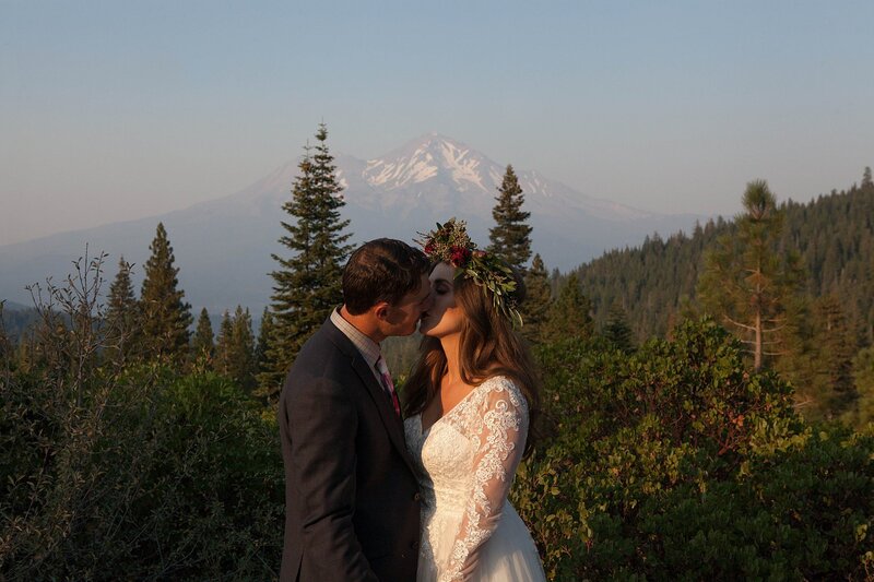 Newly eloped couple kissing in front of Mt. Shasta