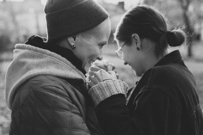 Pari seisoo vastakkain ja pitelee toisiaan käsistä ja nauraa Kalliossa Helsingissä