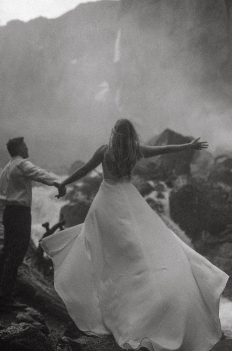 A groom and bride in wedding dress in the San Juans under a Bridal Veil Falls in Telluride