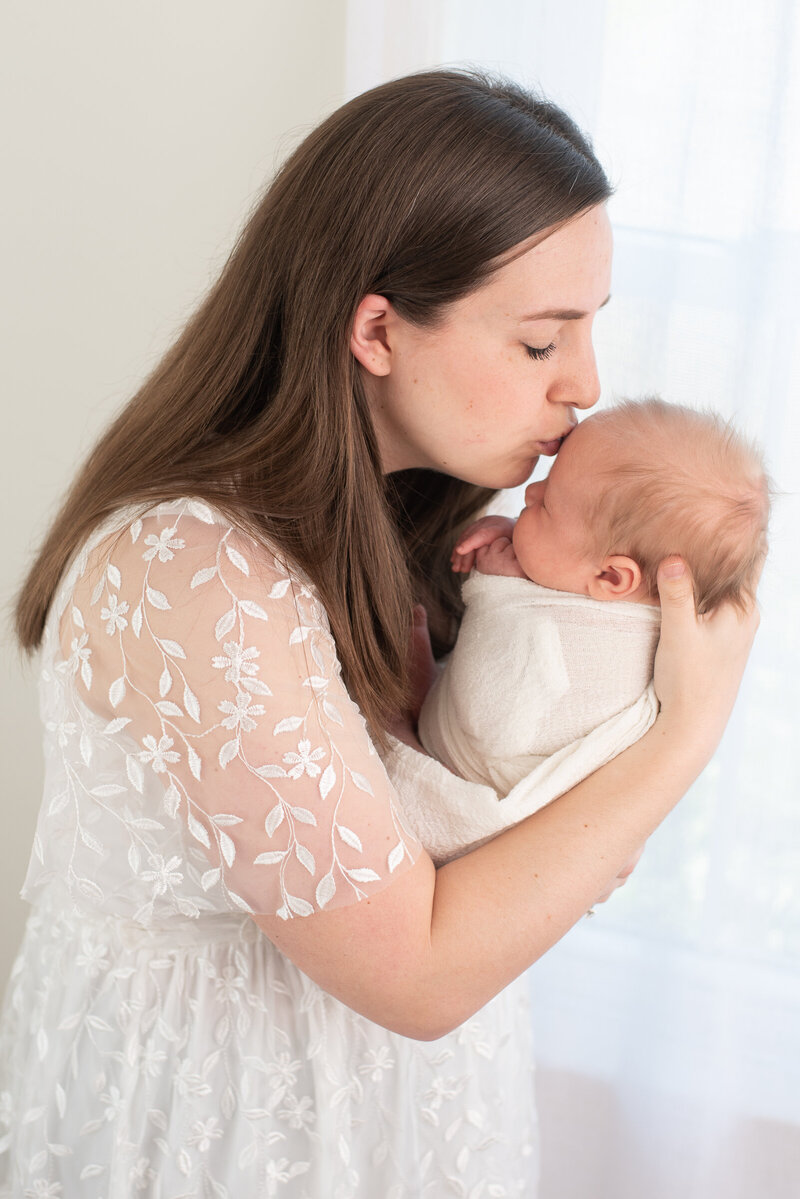 A new mom kissing her newborn baby boy at his newborn session in Canton, CT.