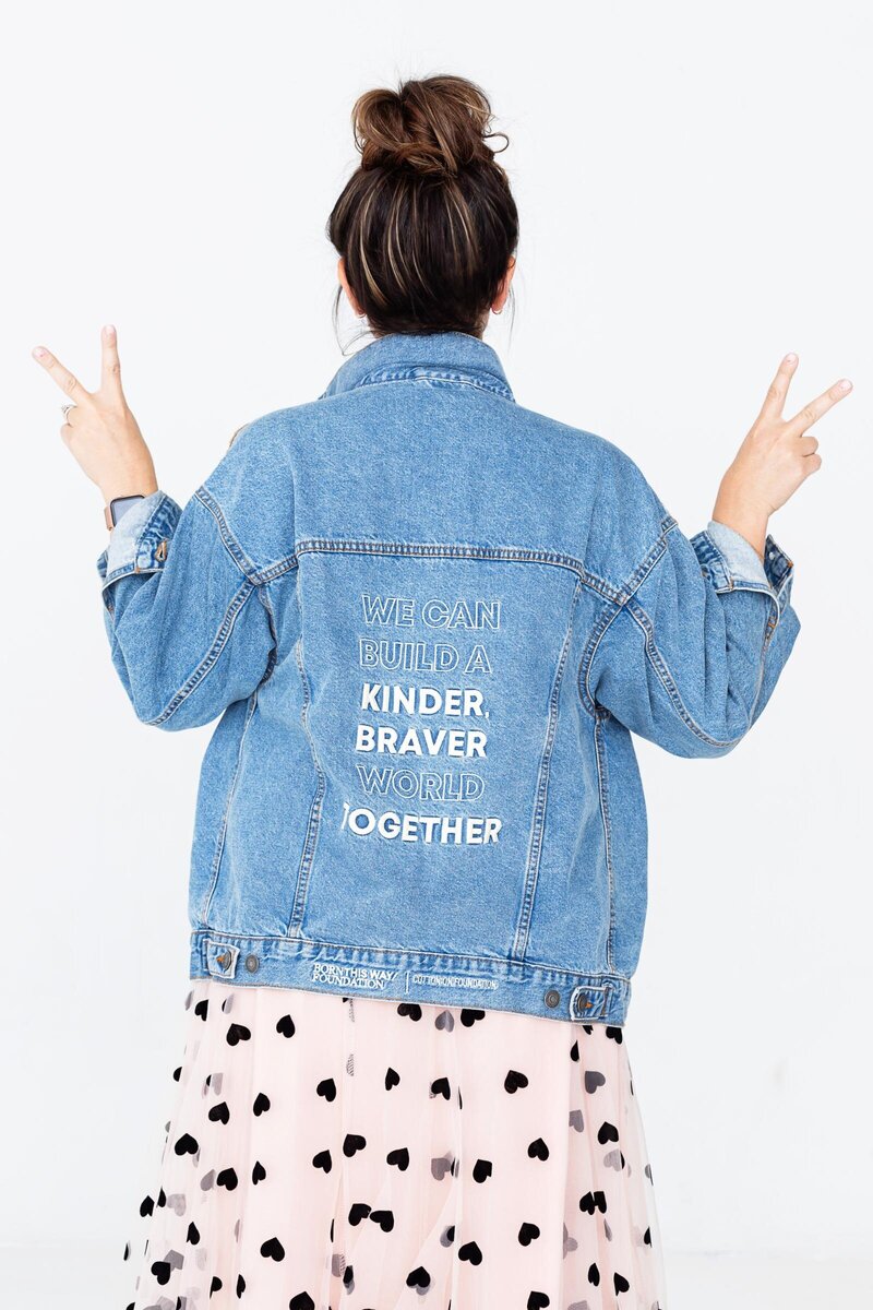 girl in denim jacket holding up the peace sign