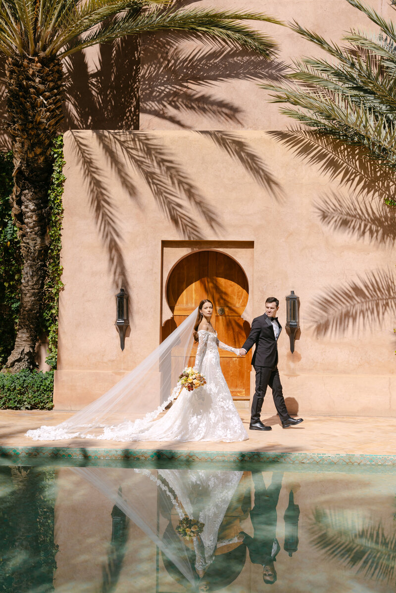bride and groom walking past pool