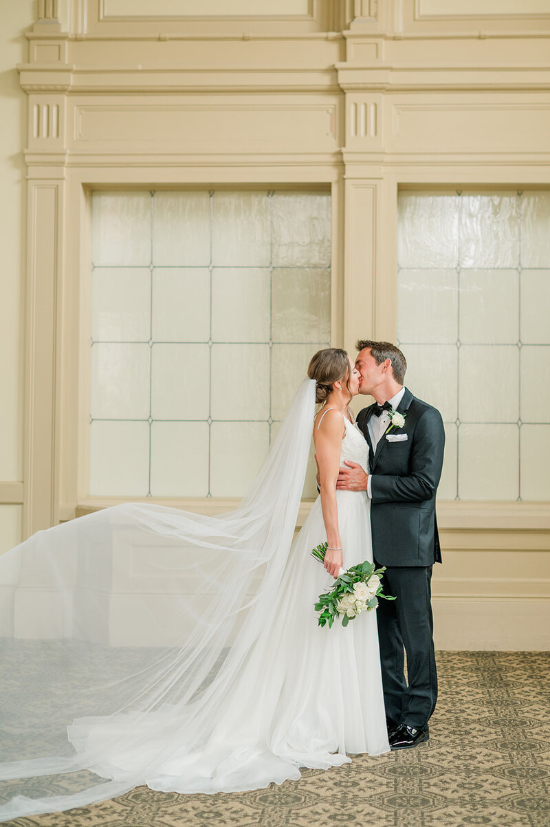 bride and groom kissing near a window
