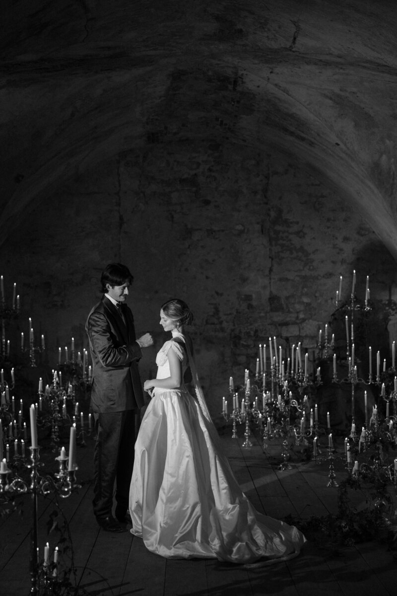 A wedding couple standing close while they are surrounded by candles 